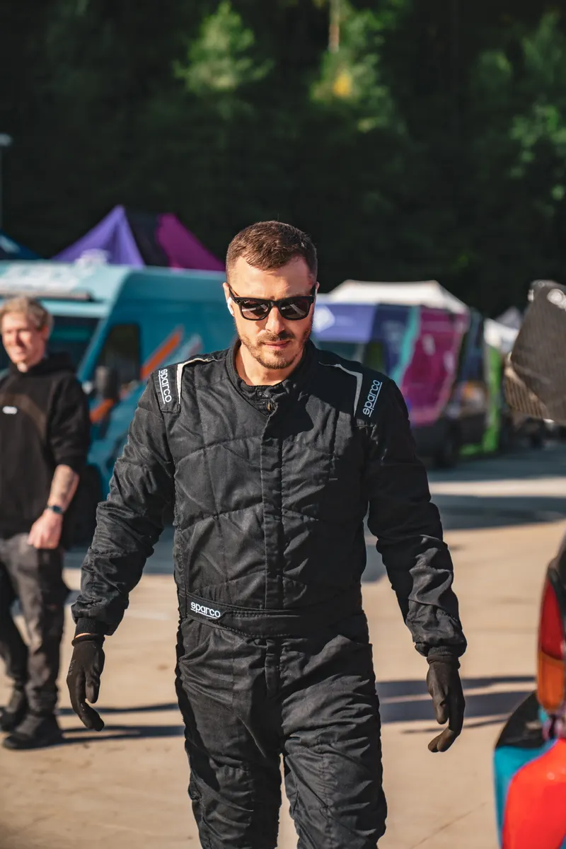 Denis Rem in race suit and gloves walking to the car